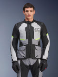 Motocyklista w kurtce Alpinestars Andes Air Drystar® w kolorach Ice Gray, Dark Gray i czarnym, z neonowymi żółtymi akcentami i siatkowymi panelami wentylacyjnymi, zestawionej z dopasowanymi spodniami i rękawicami motocyklowymi, odzież adventure touring