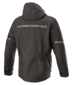 Kurtka Alpinestars Sirius Drystar® Techshell, kurtka motocyklowa, Melange Black, widok z tyłu ze zintegrowanym kapturem, odblaskowy pasek z logo Alpinestars, elastyczna talia i wydłużony tył dla lepszej osłony podczas jazdy.