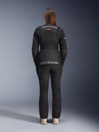 Kobieta ubrana w kurtkę Alpinestars Stella Andes Air Drystar® i pasujące spodnie, kolor czarny, widok z tyłu prezentujący duże szare logo Alpinestars na dolnej kieszeni, małe czerwone logo z gwiazdą na górze pleców, siatkowe panele wentylacyjne i odblaskowe detale do adventure touring