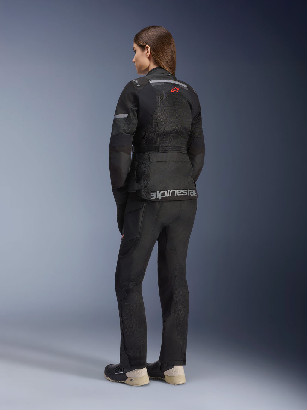 Alpinestars Stella Andes Air Drystar® Jacket, damska motocyklowa kurtka turystyczna, czarna, widok z tyłu w zestawie z dopasowanymi spodniami i butami, duże panele wentylacyjne z siatki mesh, czerwone logo z gwiazdą oraz srebrny napis Alpinestars w dolnej części pleców.
