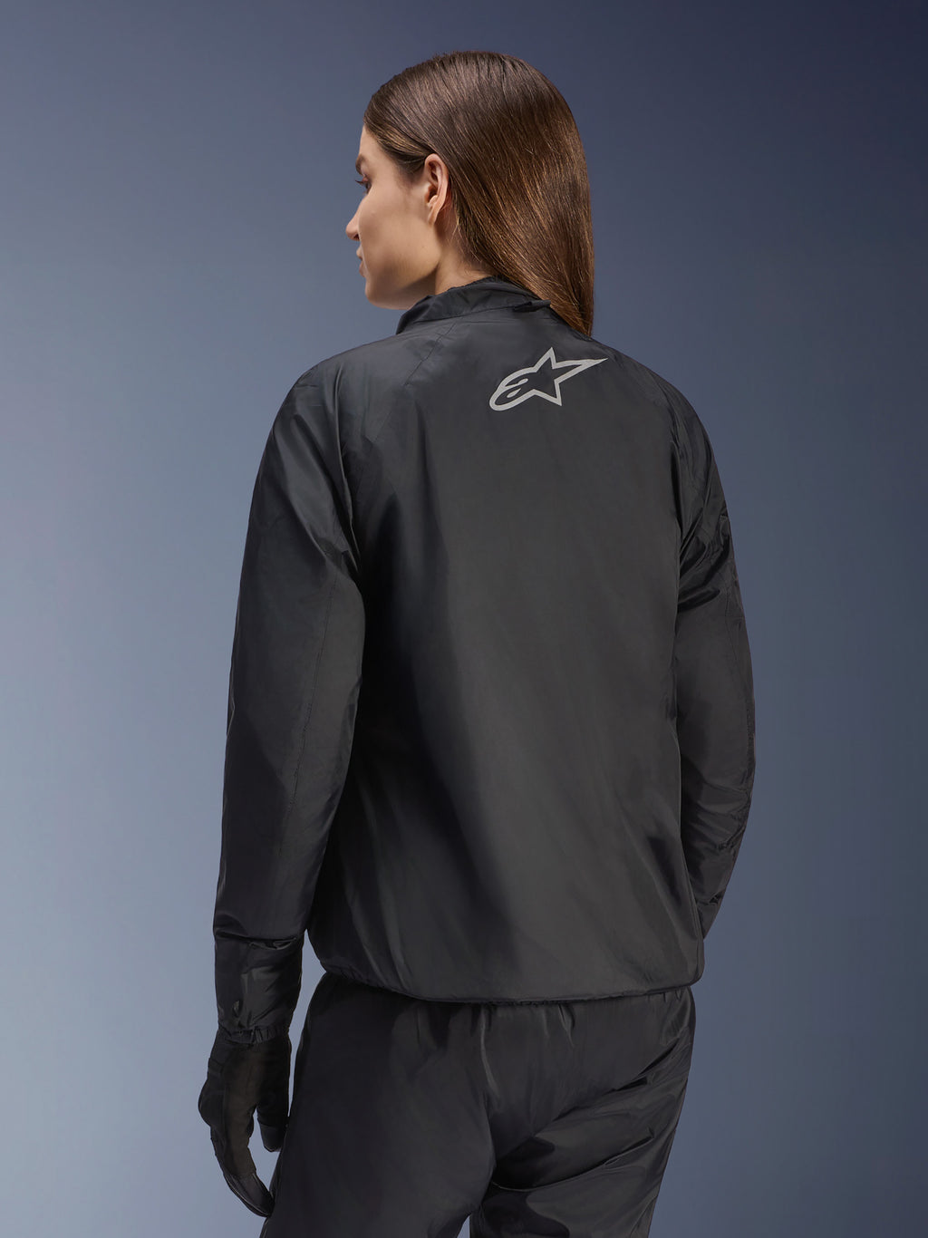 Kurtka Alpinestars Stella Andes Air Drystar®, damska kurtka motocyklowa, czarna, widok z tyłu pokazujący srebrne logo gwiazdy, zestawiona z czarnymi spodniami i rękawicami, lekka wodoodporna odzież turystyczna