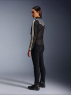 Modelka widziana z boku i z tyłu w kurtce Alpinestars Stella T-Dyno WR w kolorze Black Dark Gray Ecru, z designem inspirowanym stylem vintage, pasami ecru na rękawach i szarym panelem na plecach, zestawiona z czarnymi spodniami i czarnymi butami motocyklowymi.