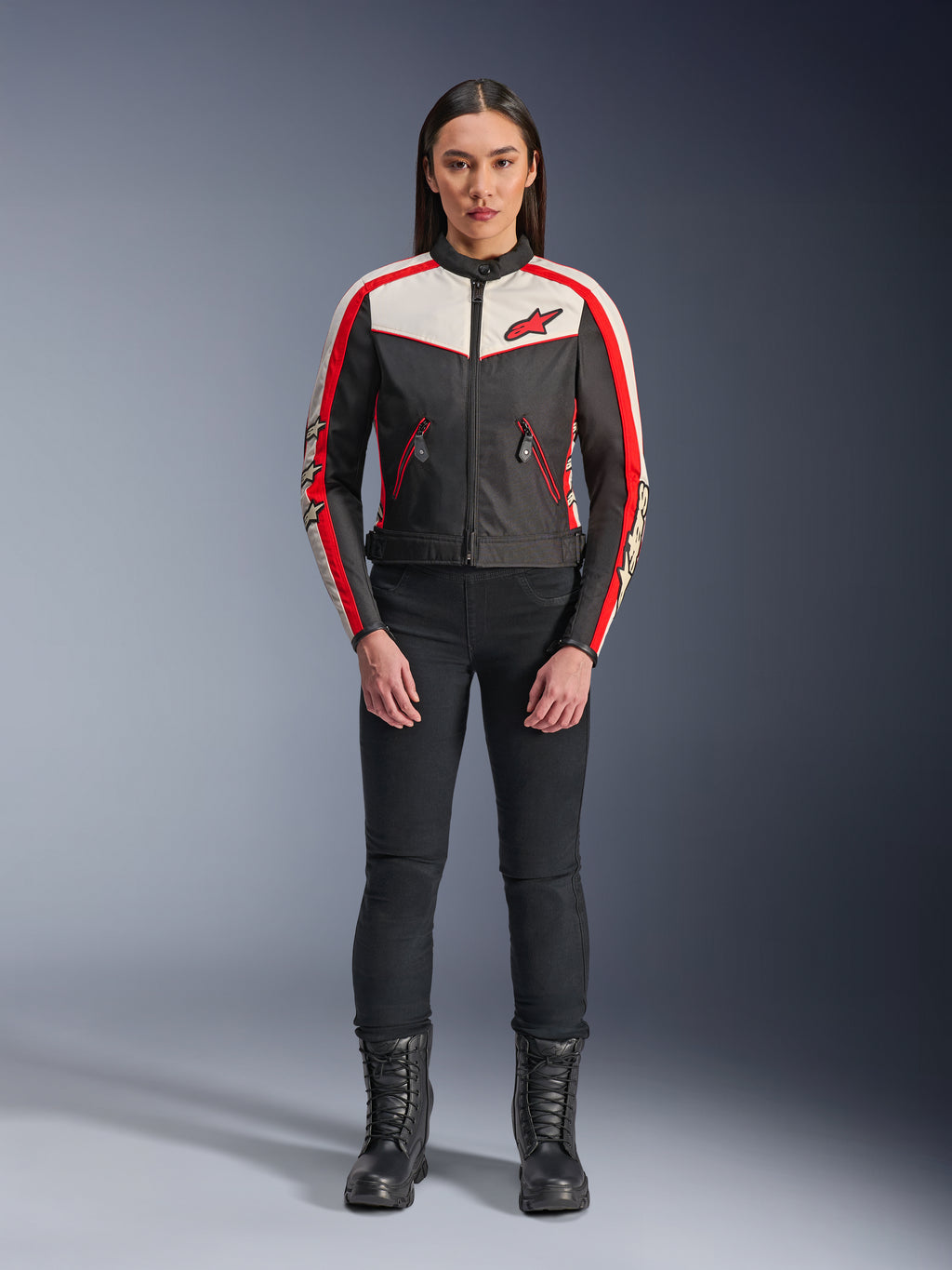 Kurtka Alpinestars Stella T-Dyno WR, damska tekstylna kurtka motocyklowa, czarna z elementami ecru i jaskrawoczerwonymi, prezentowana przez modelkę w czarnych spodniach i butach, design inspirowany stylem vintage z czerwonym logo Alpinestars i kontrastowymi panelami.