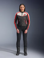 Kurtka Alpinestars Stella T-Dyno WR, damska tekstylna kurtka motocyklowa, czarna z elementami ecru i jaskrawoczerwonymi, prezentowana przez modelkę w czarnych spodniach i butach, design inspirowany stylem vintage z czerwonym logo Alpinestars i kontrastowymi panelami.