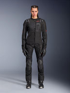 Alpinestars Stella ST-2 Air Jacket, czarna, widok studyjny całej sylwetki motocyklistki w dopasowanych czarnych spodniach motocyklowych i rękawicach, panele z siatki o wysokim przepływie powietrza, czerwone detale logo, nowoczesny design turystyczny