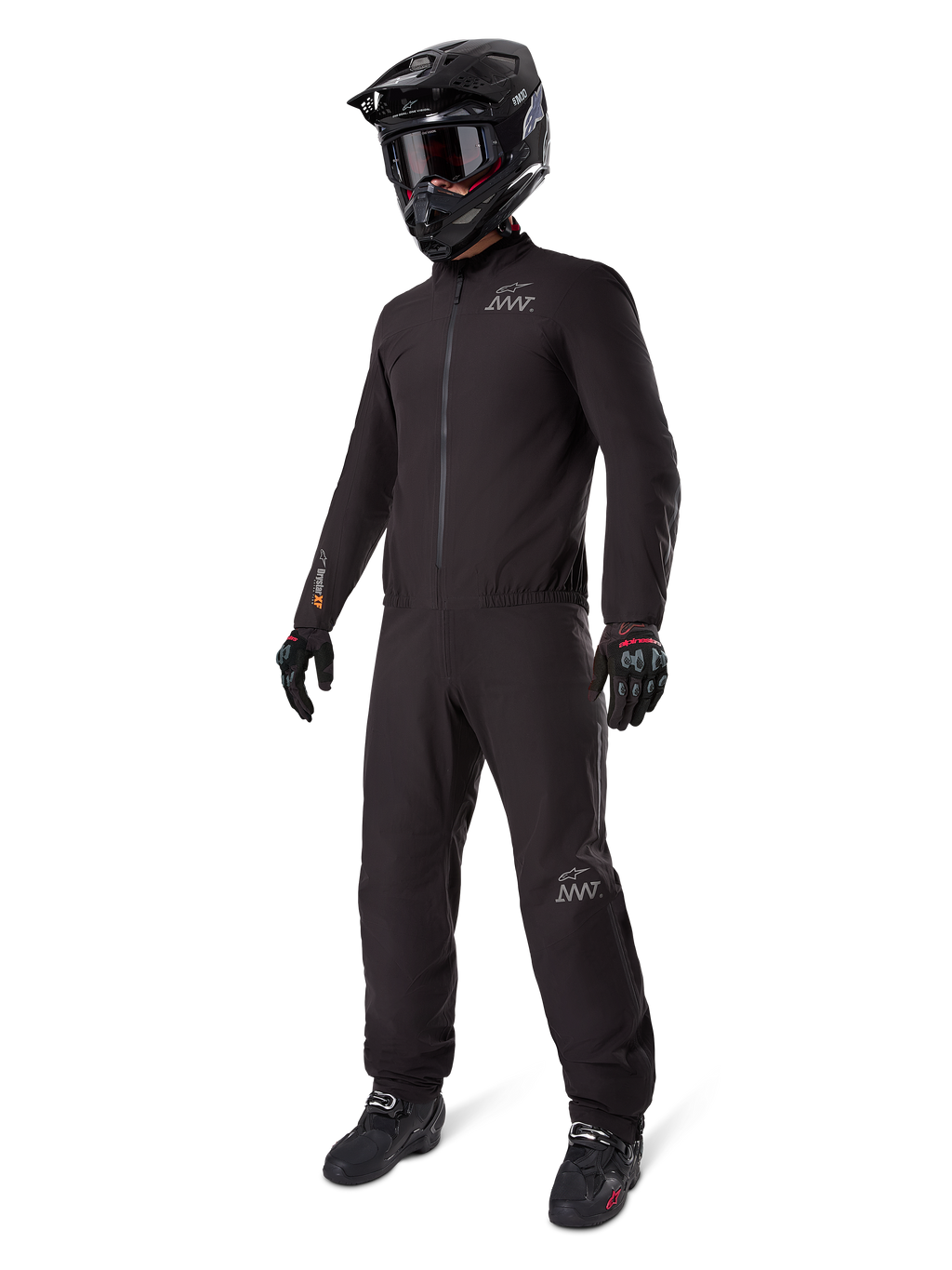 Alpinestars AMT-8 Stretch Drystar XF Liner, pełny czarny kombinezon turystyczny adventure, wodoodporna i wiatroszczelna kurtka i spodnie, zestawiony z czarnym kaskiem adventure, goglami, rękawicami i butami motocyklowymi, z logo AMT oraz Drystar XF na rękawach i nogawkach.