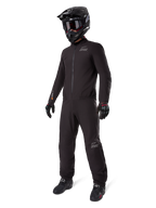 Alpinestars AMT-8 Stretch Drystar XF Liner, pełny czarny kombinezon turystyczny adventure, wodoodporna i wiatroszczelna kurtka i spodnie, zestawiony z czarnym kaskiem adventure, goglami, rękawicami i butami motocyklowymi, z logo AMT oraz Drystar XF na rękawach i nogawkach.