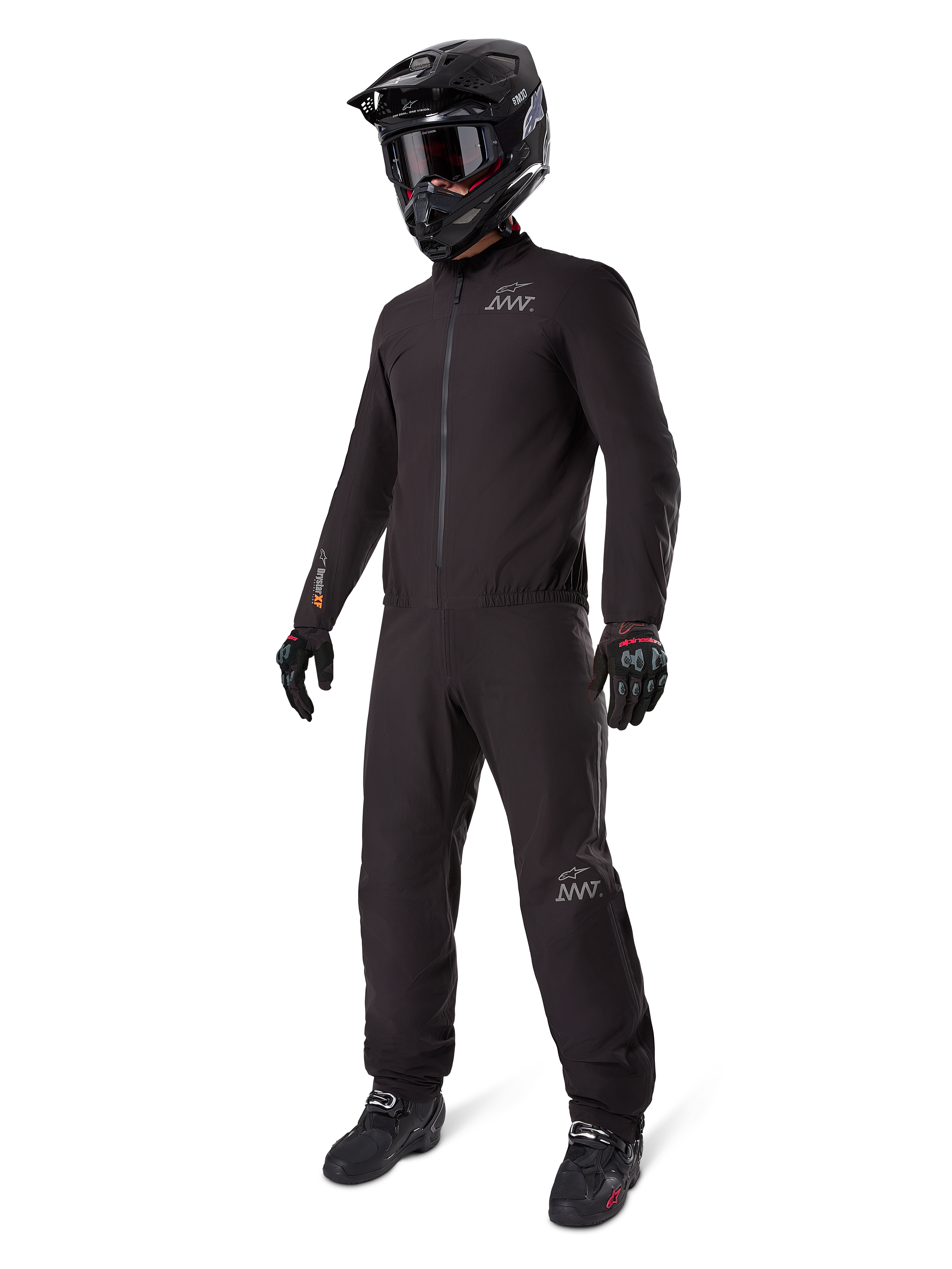Alpinestars AMT-8 Stretch Drystar XF Liner, pełny czarny kombinezon turystyczny adventure, wodoodporna i wiatroszczelna kurtka i spodnie, zestawiony z czarnym kaskiem adventure, goglami, rękawicami i butami motocyklowymi, z logo AMT oraz Drystar XF na rękawach i nogawkach.