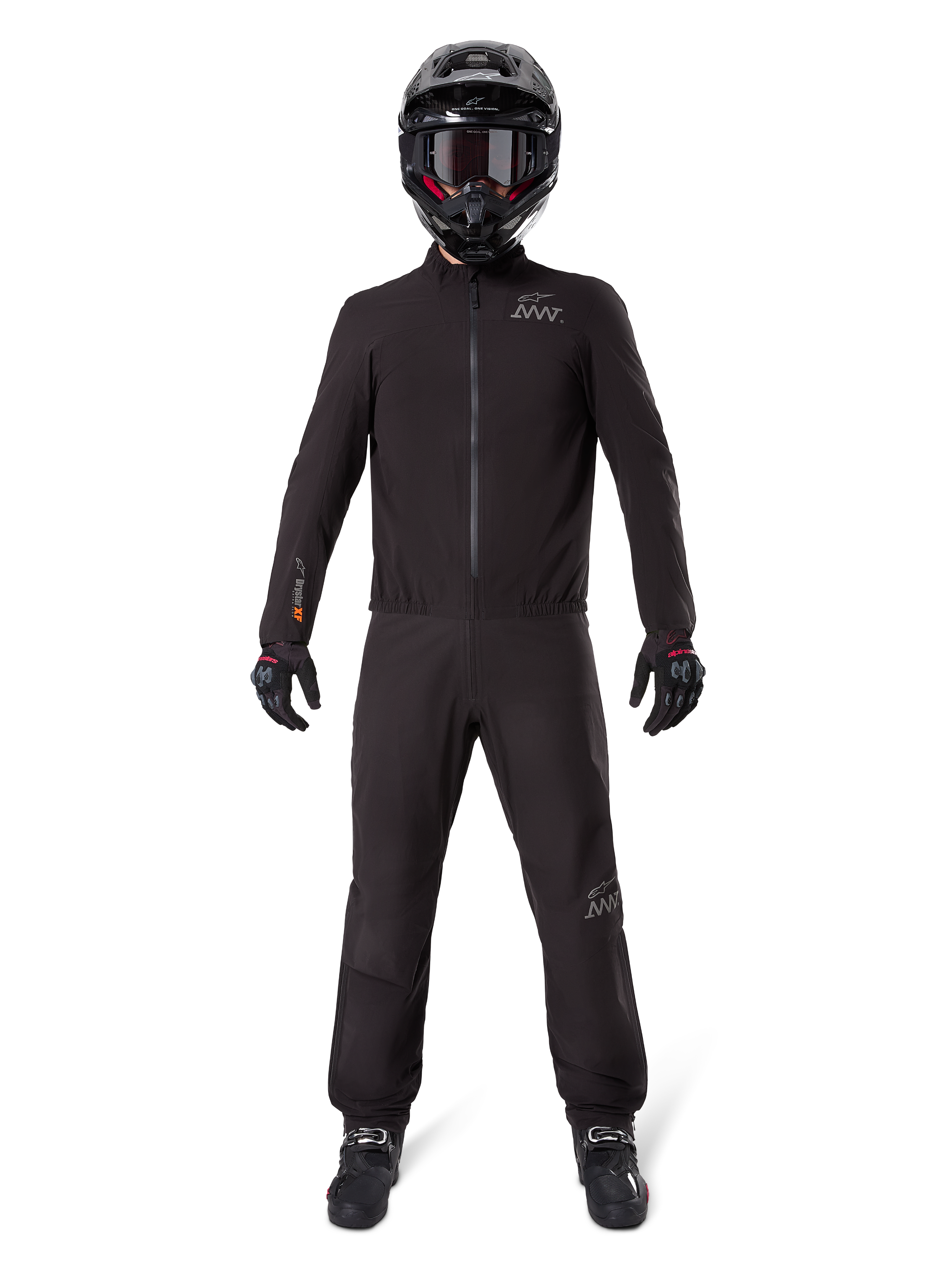 Motocyklista ubrany w podszewkę spodni Alpinestars AMT-8 Stretch Drystar® XF i pasującą kurtkę, czarny wodoodporny i wiatroszczelny strój techniczny, czarny kask, rękawice i buty, elegancki design adventure touring