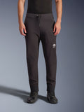Spodnie Alpinestars Aeroshell, czarne motocyklowe spodnie softshellowe, sportowy krój typu jogger z troczkiem w pasie i elastycznymi mankietami, białe logo Astars, noszone z czarnymi butami motocyklowymi, nowoczesna odzież typu crossover do użytku szosowego i casualowego