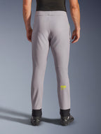 Alpinestars Aeroshell Pants, spodnie motocyklowe, szare i żółte neonowe, widok z tyłu przedstawiający żółte logo Astars na łydce, czarne elastyczne ściągacze na kostkach, nowoczesny design softshell do jazdy szosowej i codziennej