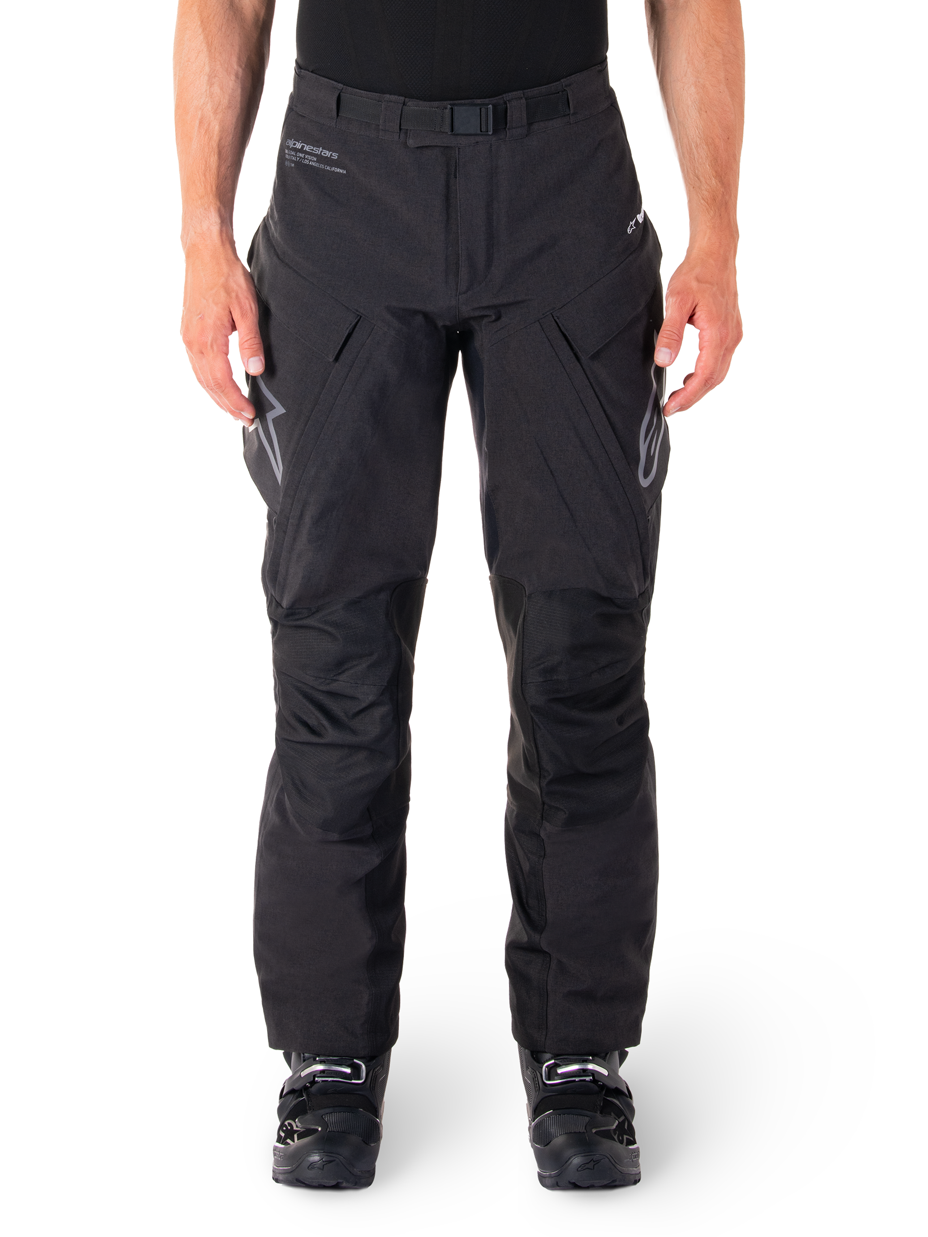 Alpinestars Hyde XT Drystar Pants, Black Adventure Touring Pants, worn by a rider with black boots, featuring grey logos on the thighs, integrated belt, reinforced knee panels, and waterproof textile construction.