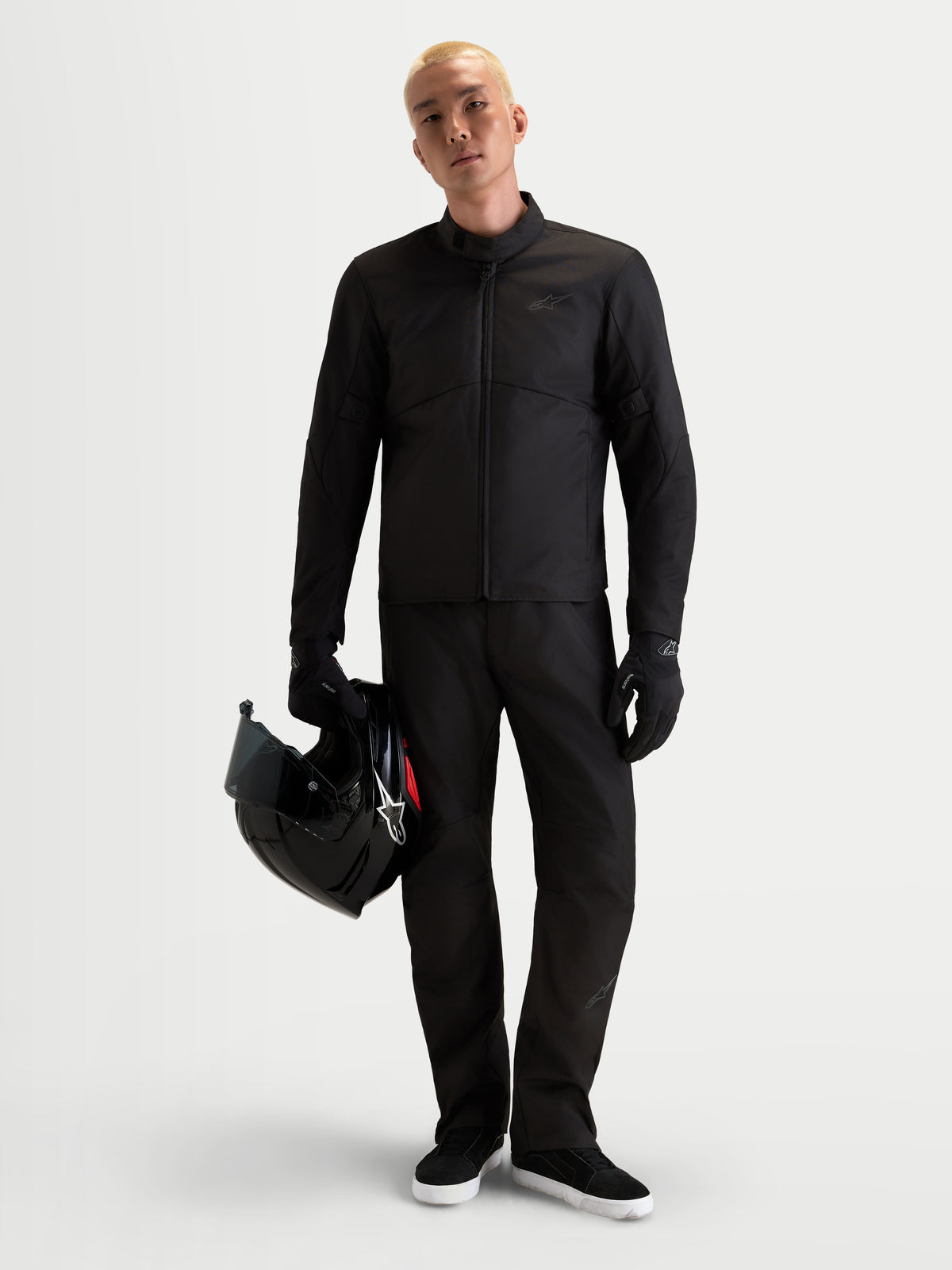 Alpinestars C 1 Waterproof spodnie motocyklowe męskie urban, czarne, prosty krój z odzieżą zimową i certyfikowaną ochroną CE, prezentowane przez model trzymający kask
