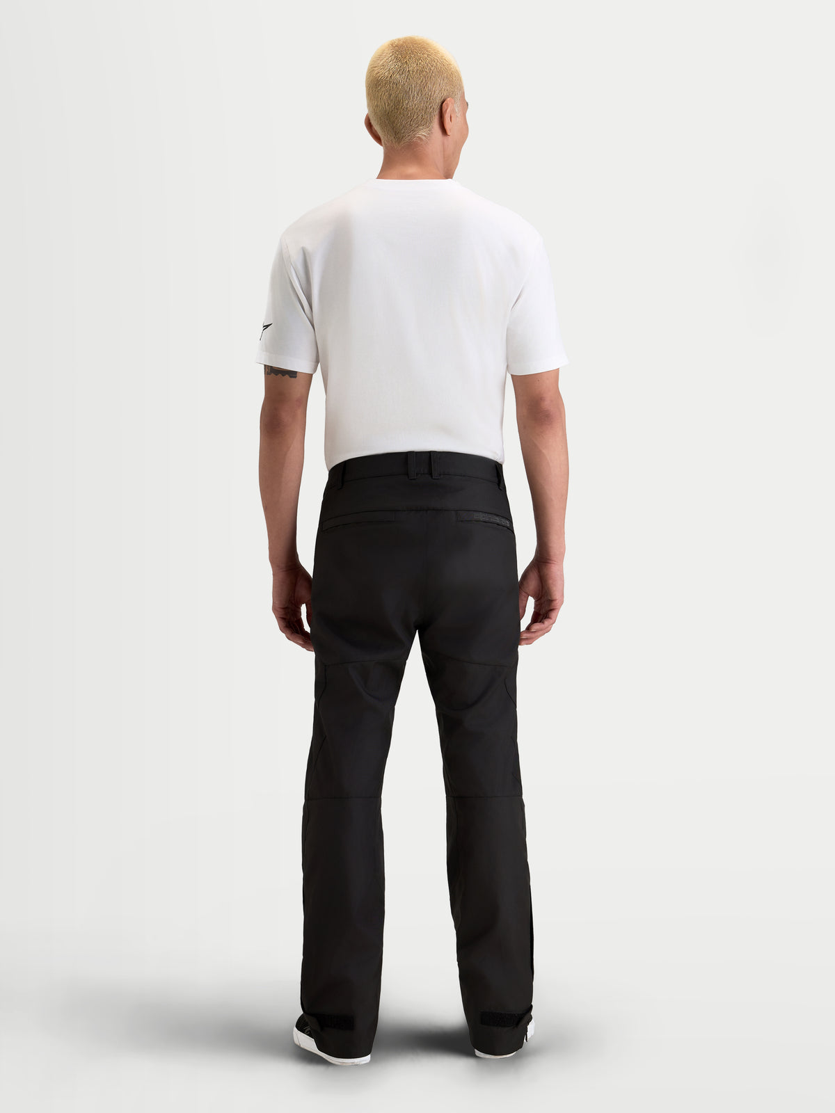 Alpinestars C 1 Waterproof spodnie motocyklowe męskie urban contemporary, czarne, widok z tyłu na modela w białym t-shircie i wodoodpornej odzieży tekstylnej
