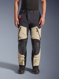 Alpinestars Halo Pro Drystar® XF Laminated Pants, Adventure Motorcycle Pants, Mastic Black, front view worn by a rider, featuring large zippered thigh vents, reinforced black knee panels, and tan textile construction, paired with black and red riding boots