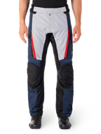 Wodoodporne spodnie Alpinestars ST-1, motocyklowe spodnie turystyczne, granatowe i jasnoszare z jaskrawoczerwonymi akcentami, czarne wzmocnione panele na kolanach, widok z przodu z czarnymi butami, wodoodporna odzież turystyczna adventure