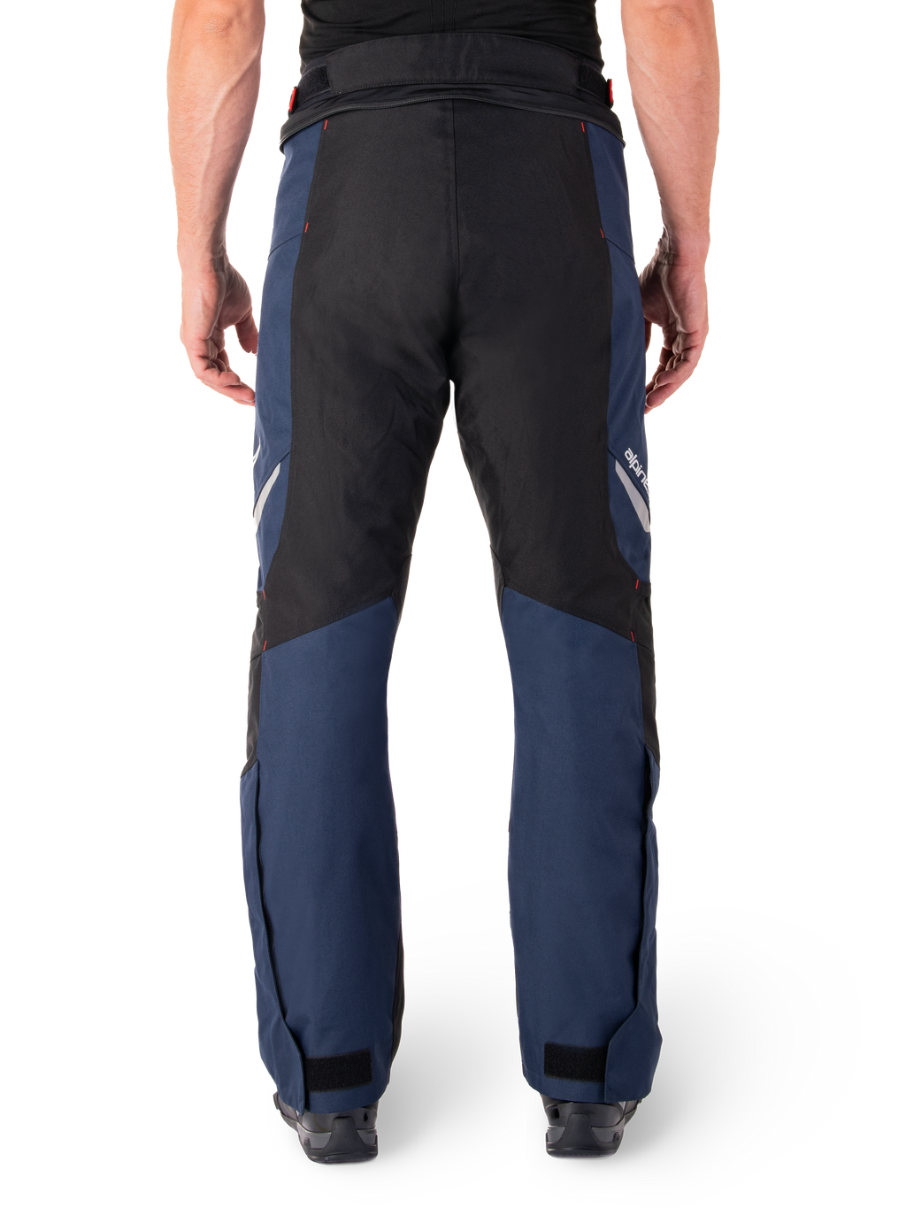 Alpinestars St-1 Waterproof Pants, motocyklowe spodnie turystyczne, ciemnoniebieskie i czarne z jaskrawoczerwonymi akcentami, widok z tyłu, opływowy krój turystyczny, wytrzymała konstrukcja tekstylna, odblaskowe logo, regulowane zapięcia na kostkach.