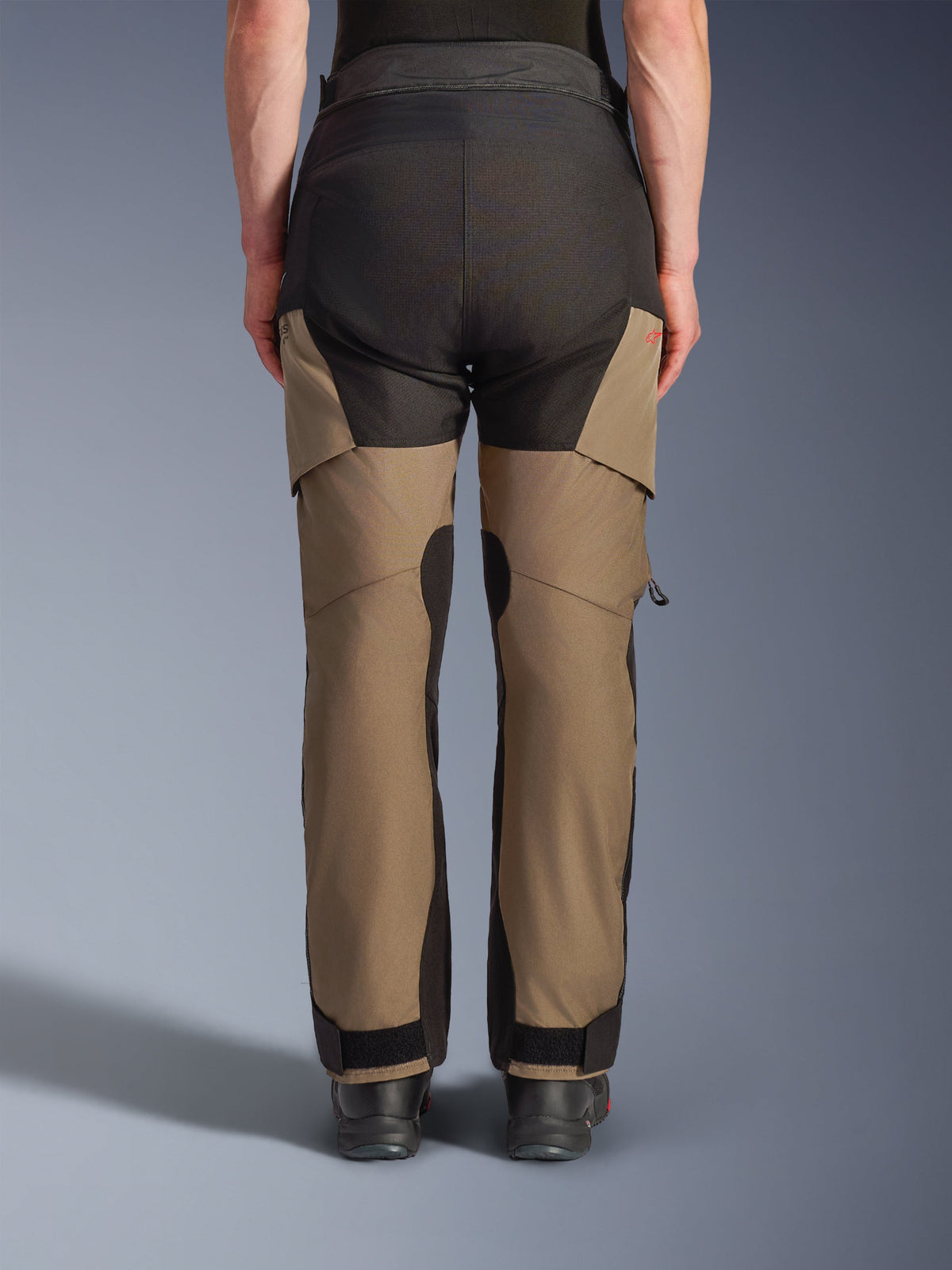 Alpinestars Andes V4 Drystar® Pants, motocyklowe spodnie turystyczne adventure, kolor Walnut i czarny, widok z tyłu ze wzmocnionymi czarnymi panelami na siedzeniu, czerwone logo i regulowane zapięcia na kostkach.