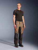 Alpinestars Andes V4 Drystar® Pants, Motorcycle Adventure Touring Pants, Walnut Black with orange accents, worn by model with black short-sleeve base layer and black boots, featuring reinforced textile panels and cargo pockets, rugged design for all-weather riding