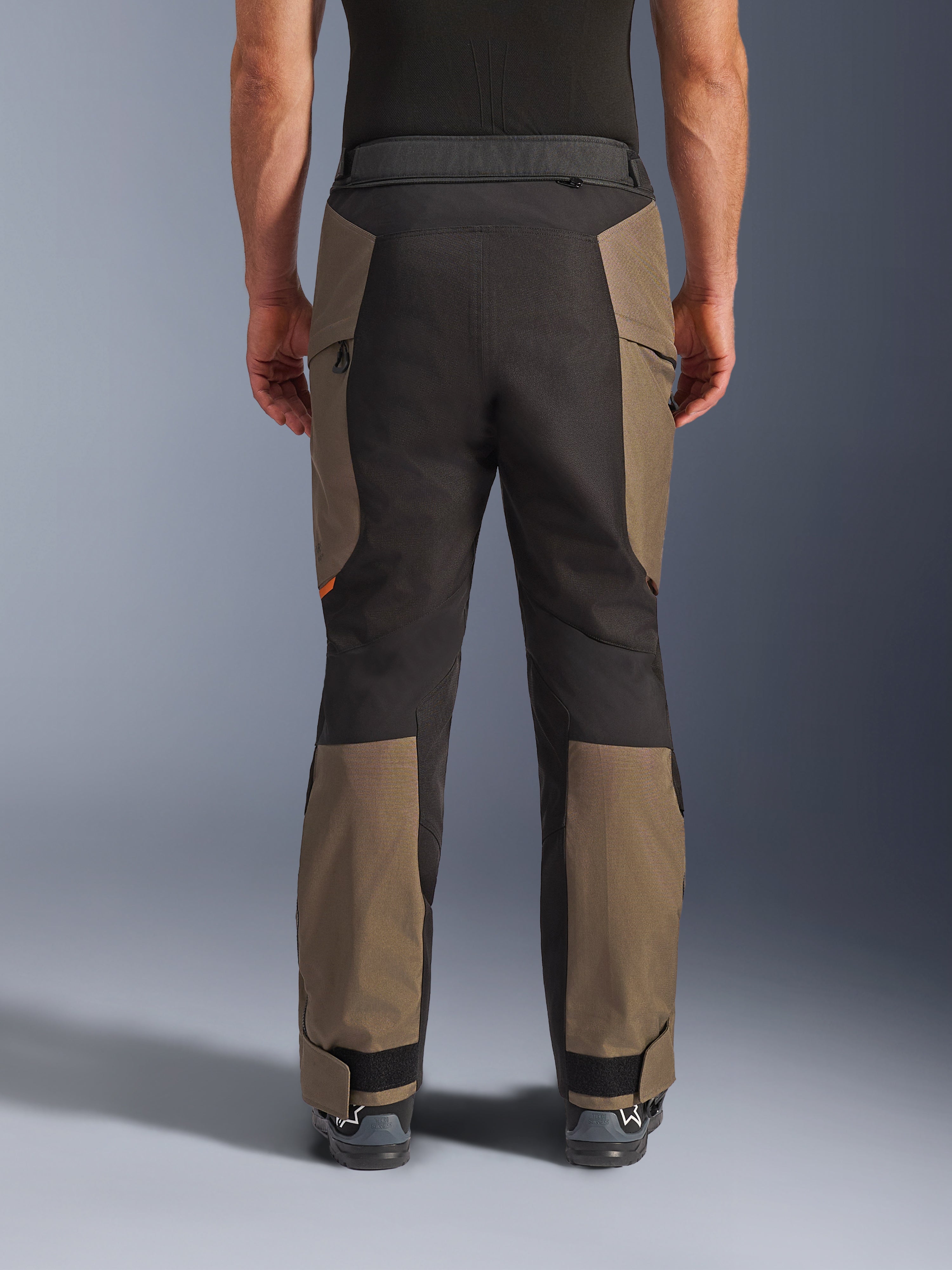 Alpinestars Cusco Drystar® Pants, spodnie motocyklowe adventure, Walnut Black, widok z tyłu na modelu, wytrzymała konstrukcja tekstylna z panelami o kontrastowych kolorach, regulowany dół nogawek i zamek w pasie do turystyki i jazdy adventure