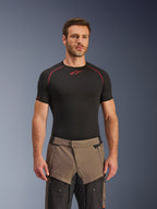Spodnie Alpinestars Cusco Drystar®, spodnie motocyklowe adventure w kolorze Walnut Black, prezentowane przez modela w czarnej koszulce termoaktywnej Alpinestars, dwukolorowa brązowo-czarna konstrukcja tekstylna z wzmocnionymi panelami do turystyki.