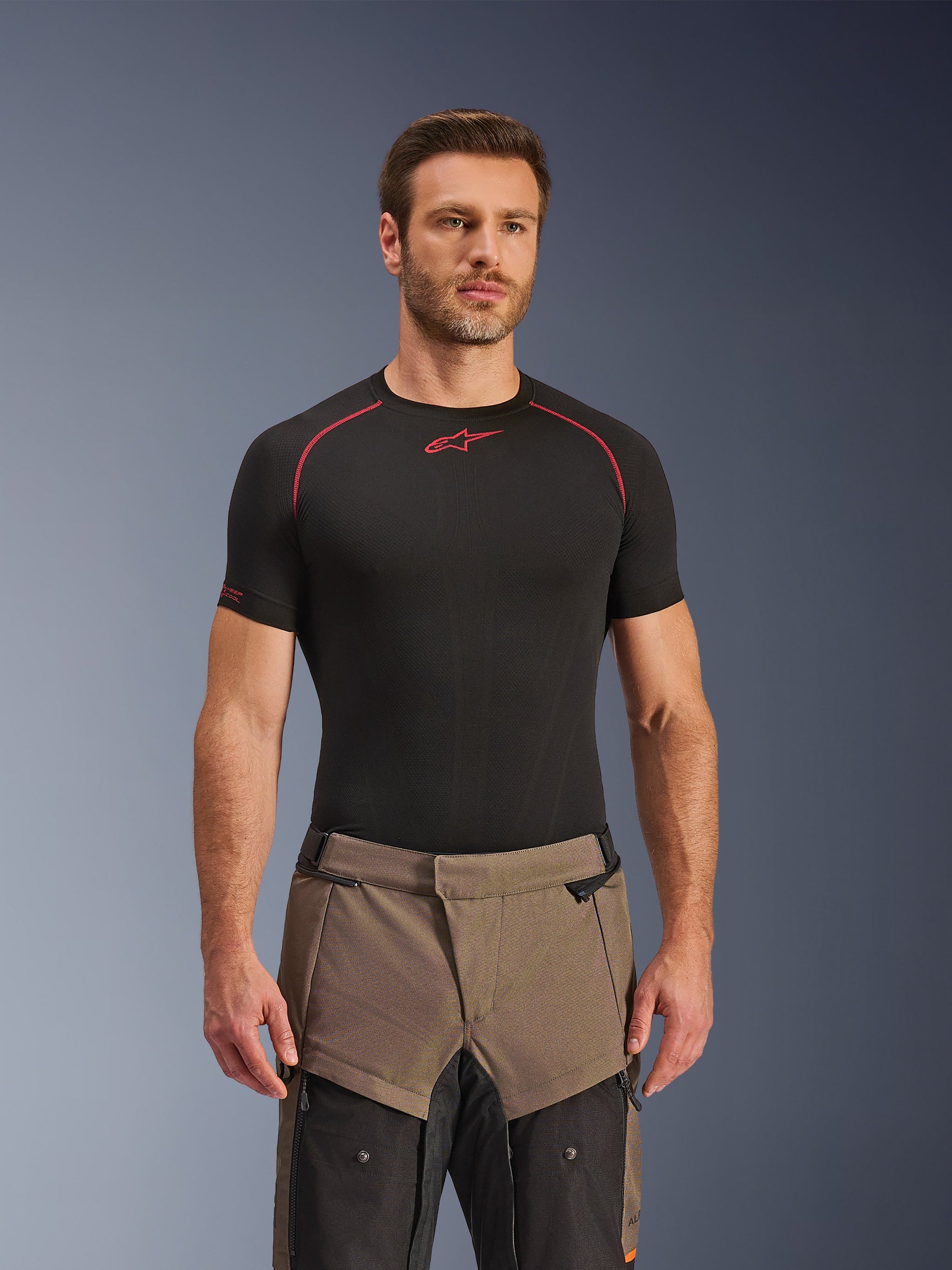 Alpinestars Cusco Drystar® Pants, Walnut Black adventure motorcycle pants, worn by a model with a black Alpinestars base layer shirt, featuring a two-tone brown and black textile design with reinforced panels for touring.