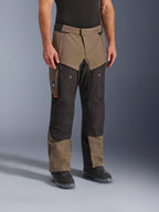 Spodnie Alpinestars Cusco Drystar®, spodnie motocyklowe adventure, Walnut Black, widoczne na modelu w czarnych butach, brązowo-czarna wielopanelowa konstrukcja z kieszeniami na zamek i wzmocnionymi kolanami do turystyki