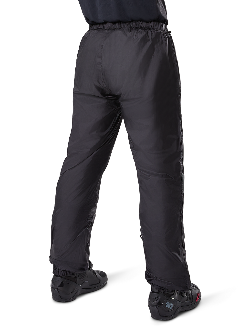 Alpinestars Bogotá Pro Drystar® 3 Seasons Pants, czarne motocyklowe spodnie adventure touring, widok z tyłu wodoodpornej podszewki Drystar® noszonej jako spodnie wierzchnie, zestawione z czarnymi butami motocyklowymi, lekka techniczna konstrukcja zapewniająca ochronę w różnych warunkach pogodowych
