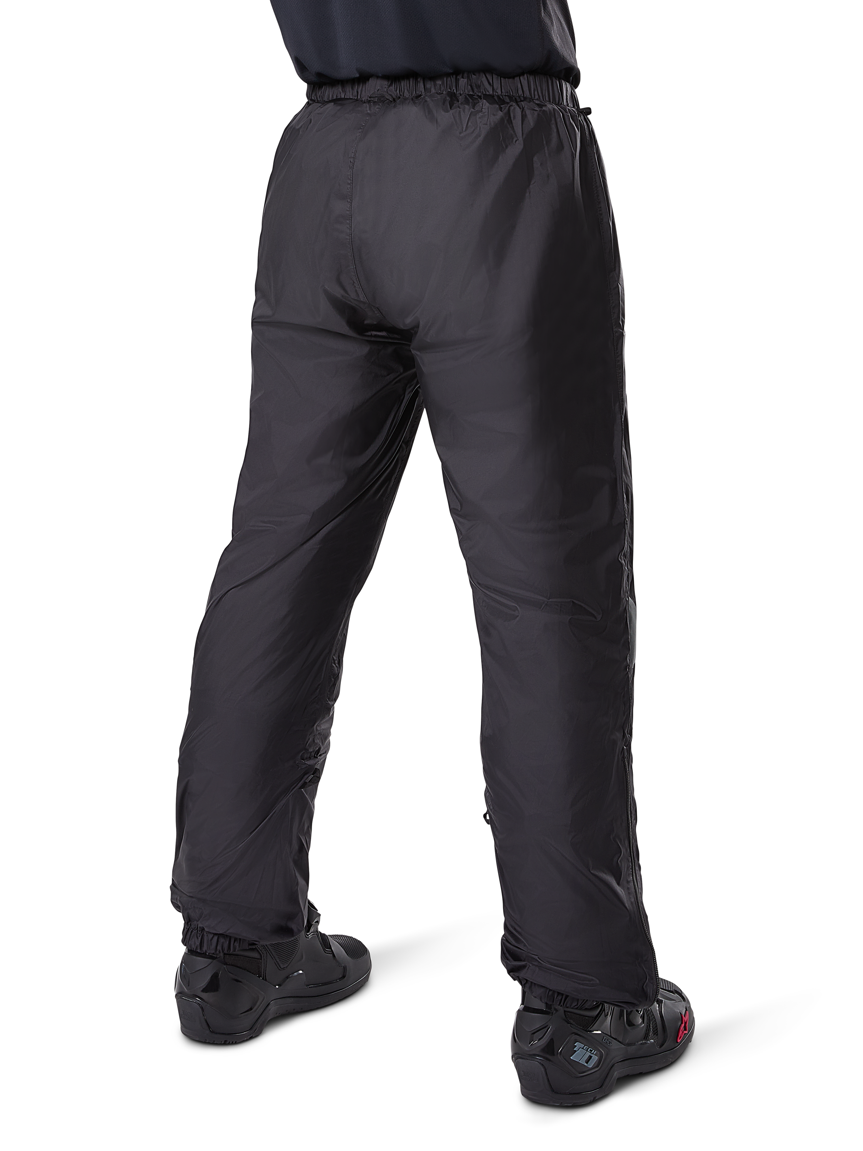 Alpinestars Bogotá Pro Drystar® 3 Seasons Pants, czarne motocyklowe spodnie adventure touring, widok z tyłu wodoodpornej podszewki Drystar® noszonej jako spodnie wierzchnie, zestawione z czarnymi butami motocyklowymi, lekka techniczna konstrukcja zapewniająca ochronę w różnych warunkach pogodowych