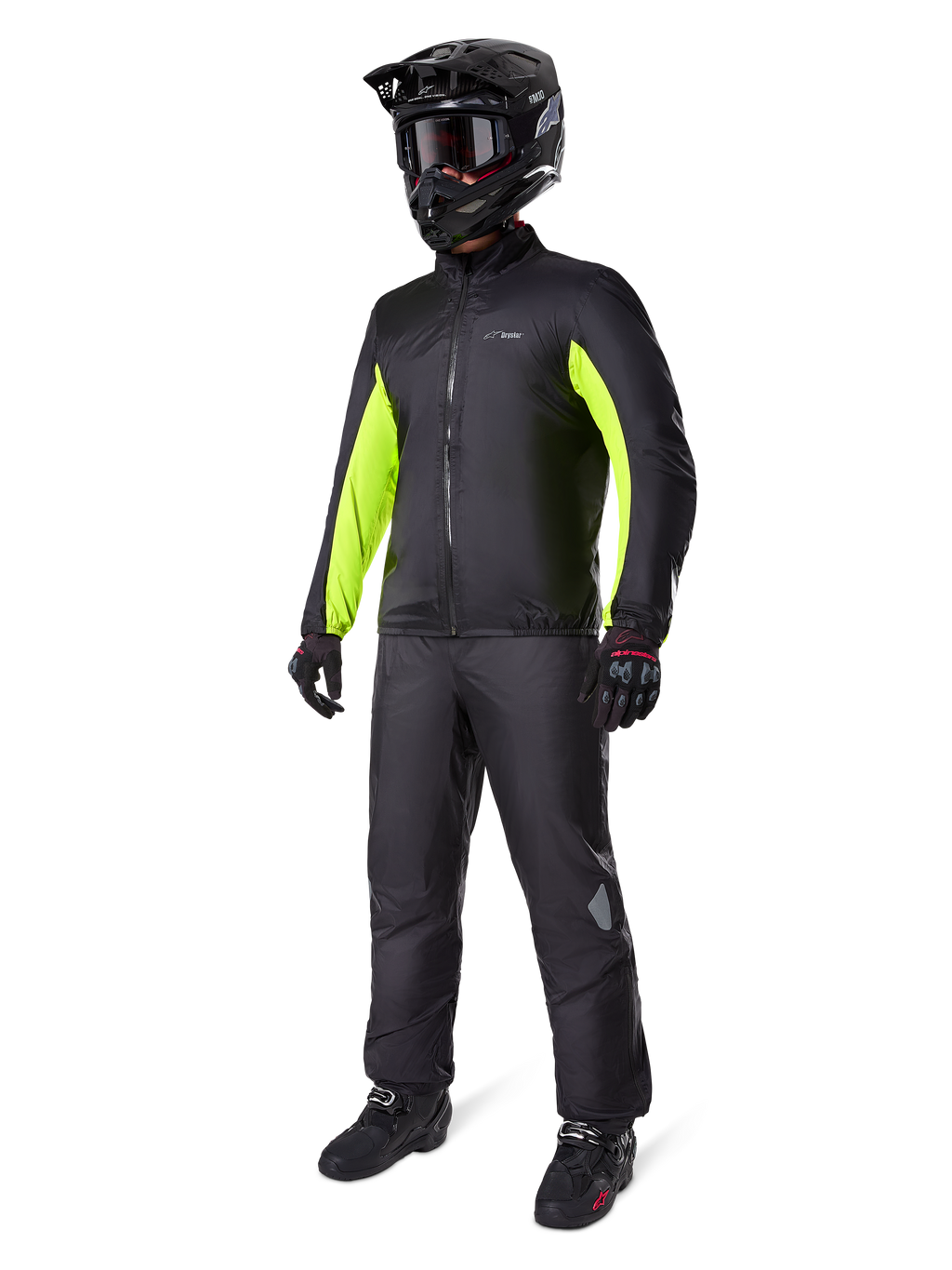 Spodnie Alpinestars Bogota' Pro Drystar® 3 Seasons, czarne, motocyklista w pełnym stroju adventure touring, w tym czarna kurtka z neonowożółtymi akcentami, czarny kask, rękawice i buty, z wodoodporną membraną Drystar® założoną na spodnie.