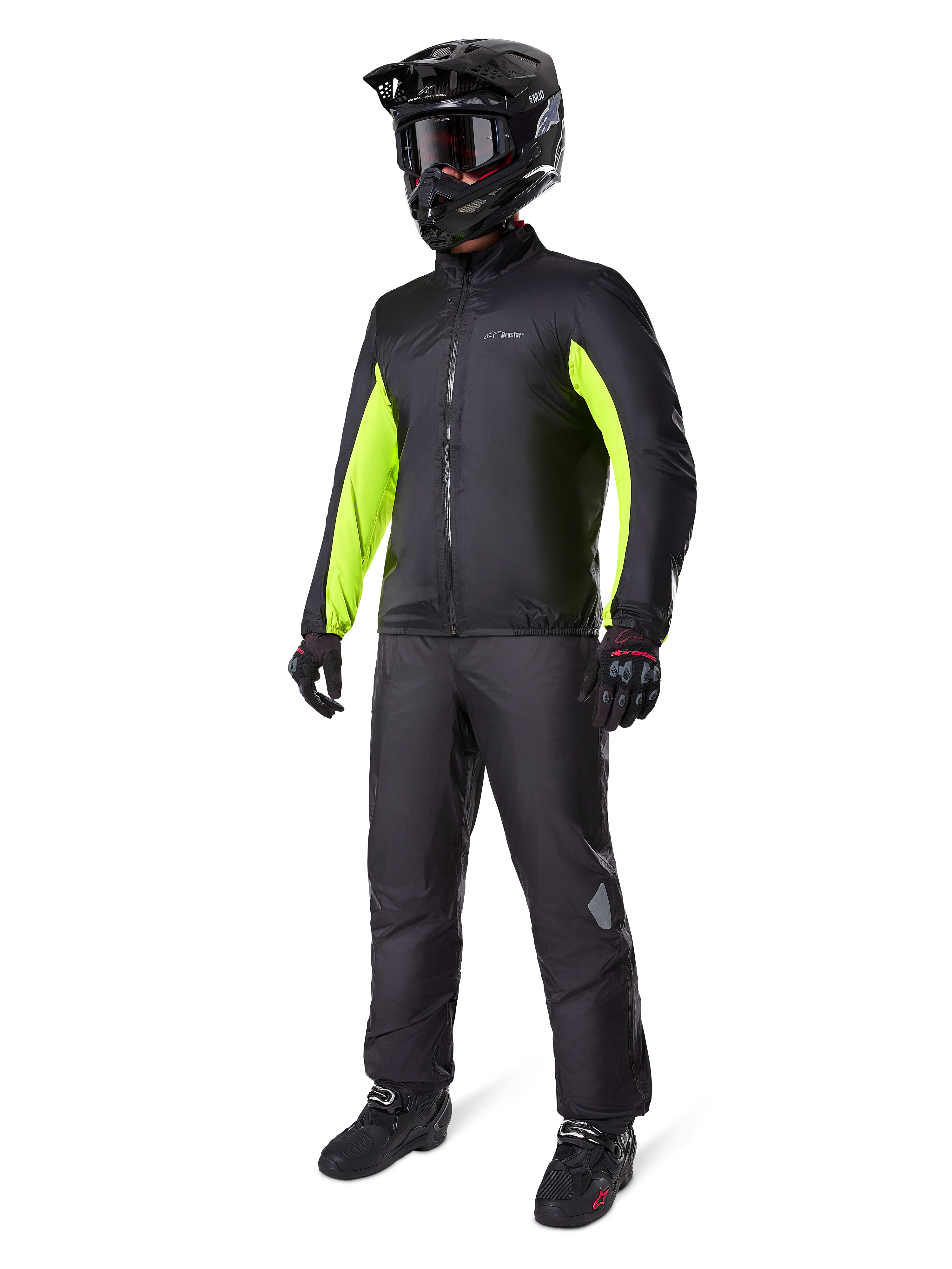 Spodnie Alpinestars Bogota' Pro Drystar® 3 Seasons, czarne, motocyklista w pełnym stroju adventure touring, w tym czarna kurtka z neonowożółtymi akcentami, czarny kask, rękawice i buty, z wodoodporną membraną Drystar® założoną na spodnie.