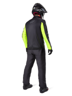 Motocyklista widziany od tyłu w czarnych spodniach Alpinestars Bogotá Pro Drystar® 3 Seasons, połączonych z czarną kurtką z neonowożółtymi rękawami, czarnym kaskiem adventure i butami, kompletny strój do turystyki przygodowej