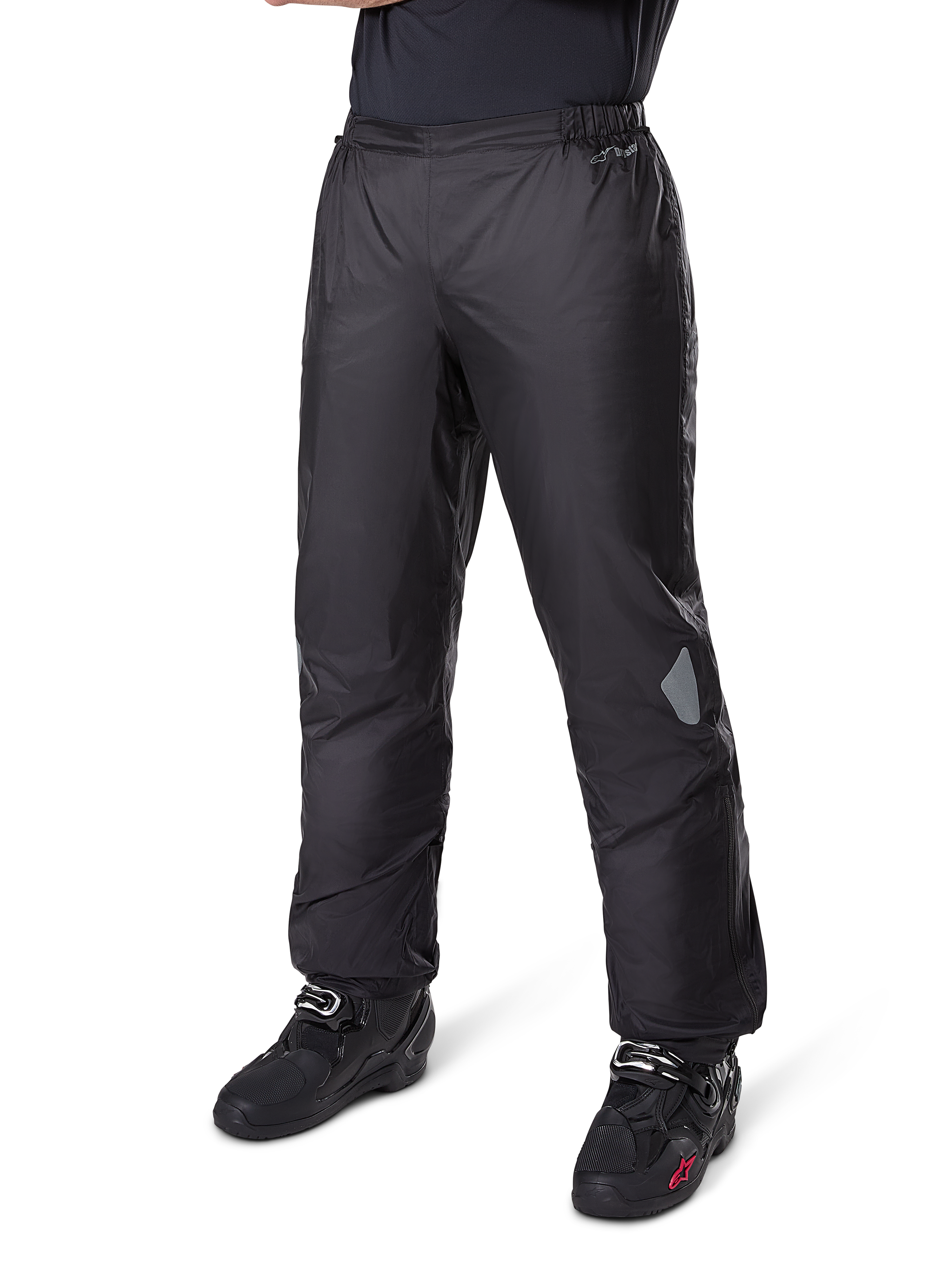 Spodnie Alpinestars Bogotá Pro Drystar® 3 Seasons, motocyklowe spodnie adventure touring, czarne, noszone z czarnymi butami motocyklowymi, z odblaskowymi naszywkami na kolanach i logo Drystar, lekka wodoodporna konstrukcja tekstylna do jazdy całorocznej