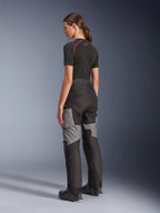 Woman Stella Andes V4 Drystar® Pants, Black and Dark Gray motorcycle adventure-touring pants, back and side view on model, featuring durable textile construction with gray reinforcement panels and a tailored fit for women riders.