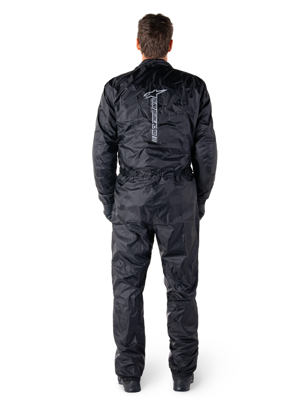 Alpinestars Hurricane Rain V2 Suit, czarny jednoczęściowy wodoodporny kombinezon motocyklowy, widok z tyłu z dużym pionowym napisem i logo Alpinestars, lekki marszczony materiał z elastycznym pasem i mankietami, zaprojektowany do ochrony podczas jazdy w deszczu.