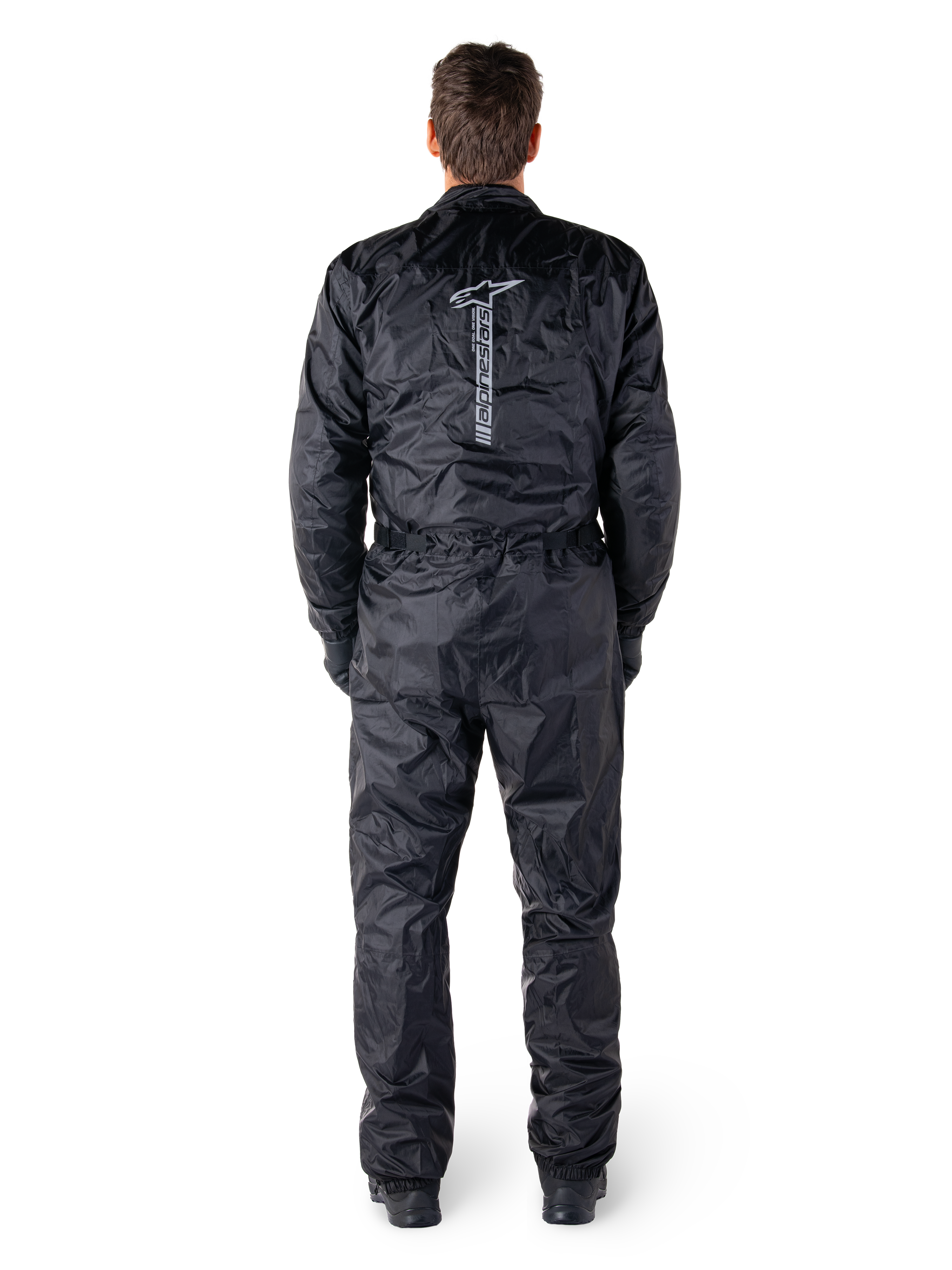Alpinestars Hurricane Rain V2 Suit, czarny jednoczęściowy wodoodporny kombinezon motocyklowy, widok z tyłu z dużym pionowym napisem i logo Alpinestars, lekki marszczony materiał z elastycznym pasem i mankietami, zaprojektowany do ochrony podczas jazdy w deszczu.