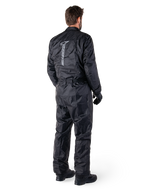 Alpinestars Hurricane Rain V2 Suit, czarny jednoczęściowy wodoodporny motocyklowy kombinezon przeciwdeszczowy, widok z tyłu z dużym pionowym odblaskowym logo, lekka wiatroodporna tkanina, noszony z czarnymi rękawicami i butami