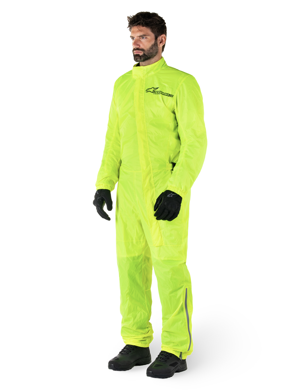 Alpinestars Hurricane Rain V2 Suit, jednoczęściowy wodoodporny kombinezon motocyklowy, żółty fluo, noszony z czarnymi rękawicami i butami, czarne logo Alpinestars na klatce piersiowej, odblaskowe detale na nogawkach