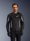 Alpinestars AST V3 Air Jacket, kurtka motocyklowa, czarna, ciemnoszara i biała, noszona przez mężczyznę w dopasowanych czarnych rękawicach, wyposażona w techniczne panele z siatki zapewniające przepływ powietrza i sportowy krój idealny do jazdy w ciepłe dni