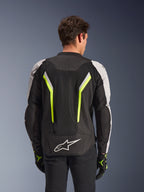 Alpinestars AST V3 Air Jacket, Black Silver Yellow Fluo, widok z tyłu na modelu, tekstylna kurtka motocyklowa z podwójnymi panelami wentylacyjnymi tech mesh, pionowymi neonowo-żółtymi pasami, srebrnymi rękawami i białym logo Alpinestars na dole pleców.