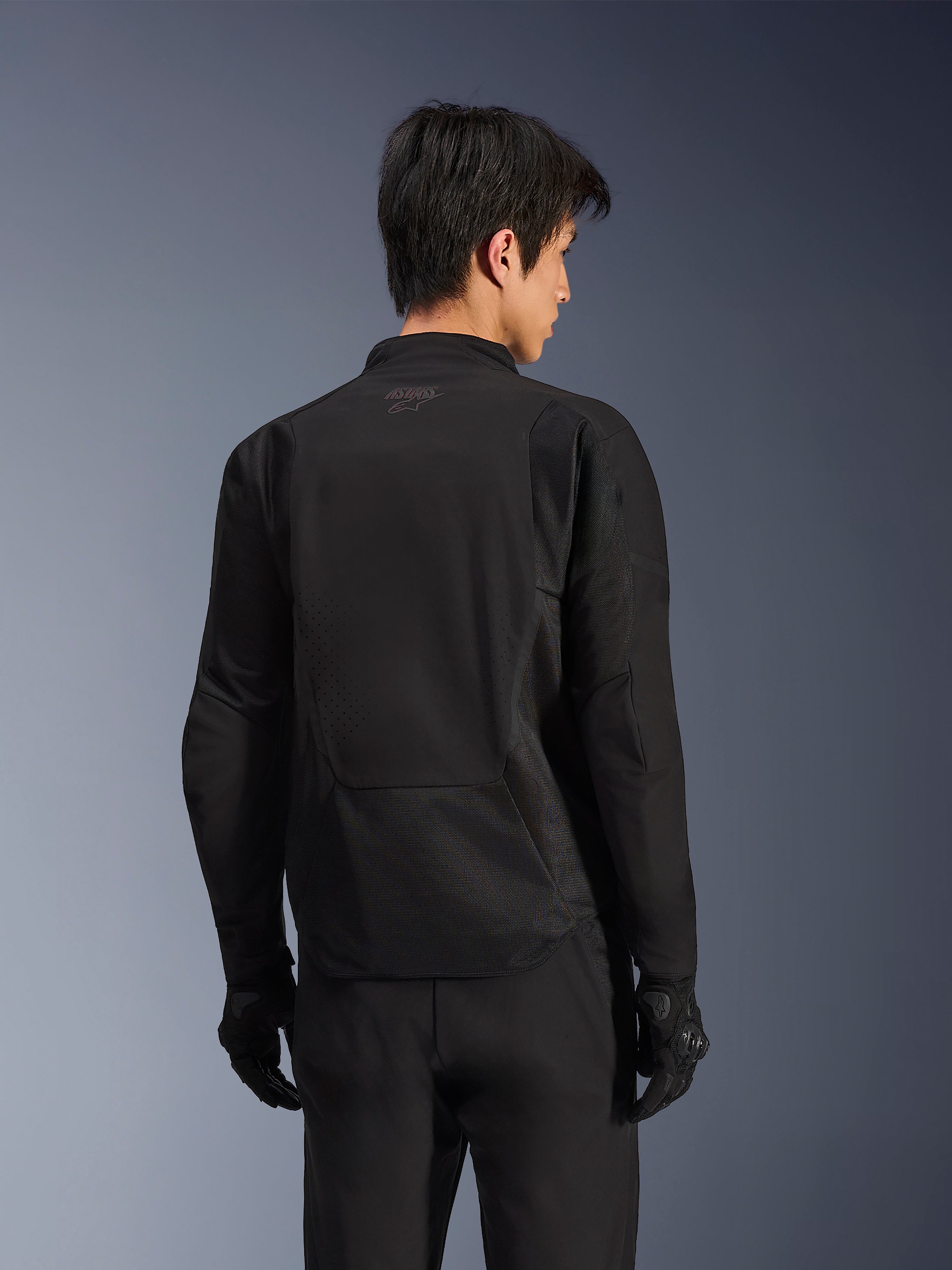 Kurtka Alpinestars Aeroshell Airflow, Black Anthracite, widok z tyłu sportowej kurtki motocyklowej z laserowo perforowanymi strefami wentylacyjnymi i panelami z siatki 2D, wydłużony tył dla lepszej osłony, noszona z czarnymi rękawicami motocyklowymi