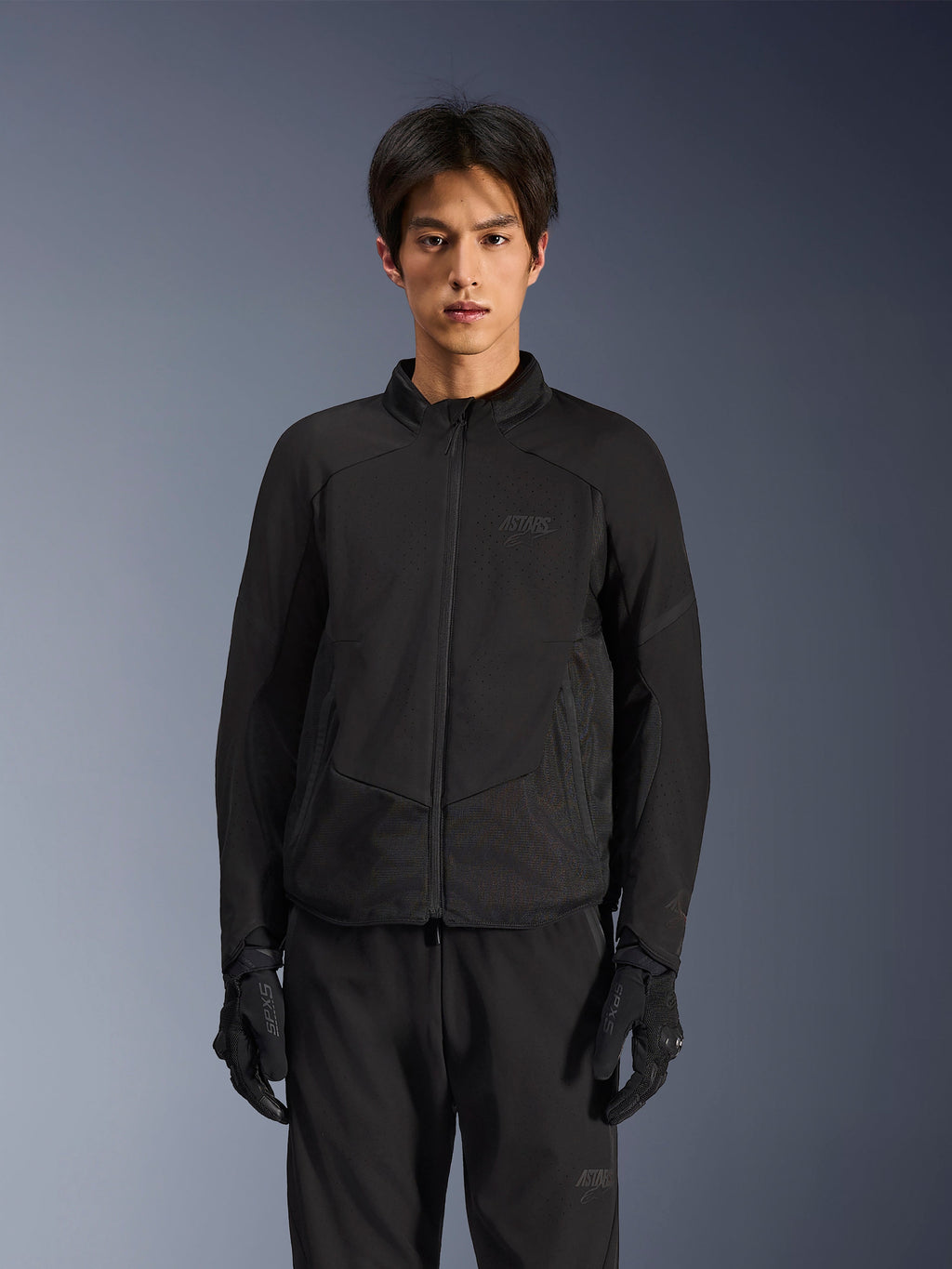 Kurtka Alpinestars Aeroshell Airflow w kolorze Black Anthracite, lekka kurtka motocyklowa z laserowo perforowaną wentylacją na klatce piersiowej i rękawach, oddychającymi panelami z siatki i dopasowanym sportowym krojem, prezentowana przez modela w czarnych rękawicach motocyklowych.