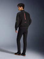 Męski model ubrany w kurtkę Alpinestars Flight Air w kolorze Black Bright Red, widok z tyłu ukazujący pionowe czerwone logo na plecach oraz konstrukcję z siatki 3D, w połączeniu z czarnymi spodniami i sneakersami, miejski styl motocyklowy