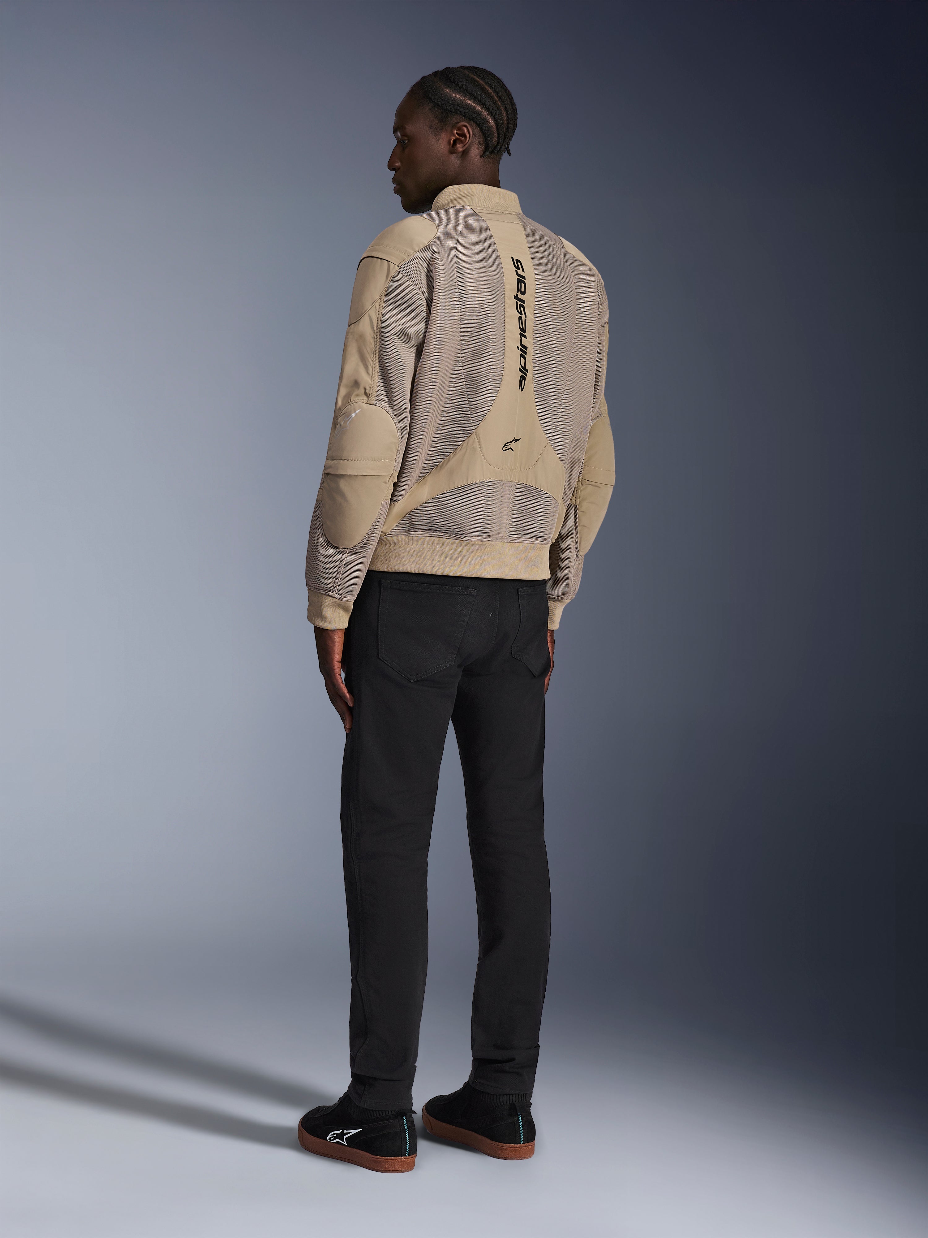 Alpinestars Flight Air Jacket, urban textile motorcycle jacket, Brown, back view showing large 3D mesh panels and vertical logo, bomber-style silhouette with ribbed collar and hem, paired with black pants and black shoes for street-inspired riding style.