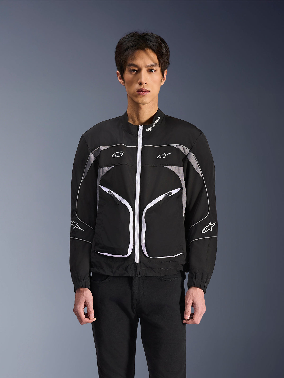 Kurtka Alpinestars Unite, minimalistyczna miejska kurtka motocyklowa, czarna i ciemnoszara z białymi akcentami, biały zamek błyskawiczny z przodu, odblaskowe lamówki, logo Alpinestars na piersi i rękawach, nowoczesny styl streetwear dla motocyklistów.