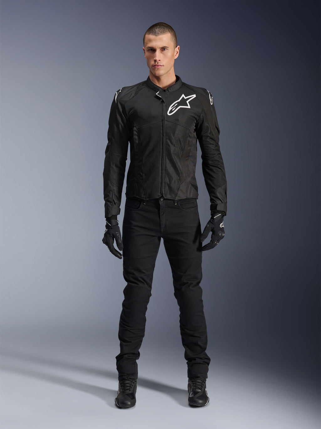 Kurtka Alpinestars Viper Air V4, czarna tekstylna kurtka motocyklowa, białe logo na klatce piersiowej i ramionach, noszona z czarnymi spodniami motocyklowymi i rękawicami, posiada panele z siatki technologicznej dla przepływu powietrza, ujęcie studyjne całej sylwetki