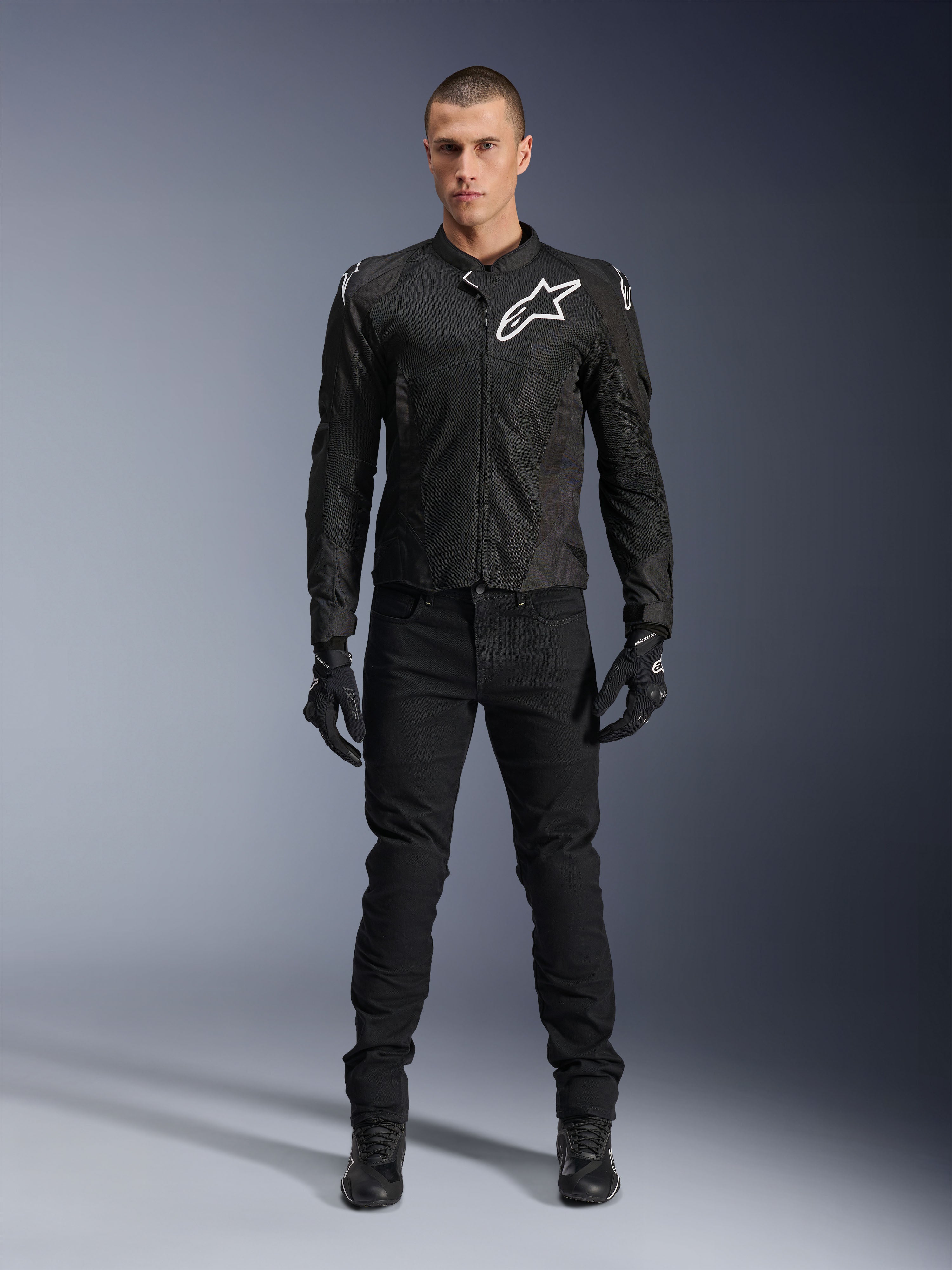 Kurtka Alpinestars Viper Air V4, czarna tekstylna kurtka motocyklowa, białe logo na klatce piersiowej i ramionach, noszona z czarnymi spodniami motocyklowymi i rękawicami, posiada panele z siatki technologicznej dla przepływu powietrza, ujęcie studyjne całej sylwetki