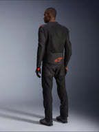 Alpinestars Viper Air V4 Jacket, motocyklista widziany od tyłu, czarno-czerwona (Black Red Fluo), pomarańczowe logo Astars na dole pleców i barkach, siatkowa konstrukcja tekstylna, czarne spodnie i buty motocyklowe