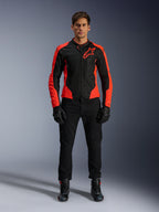 Męski model w kurtce Alpinestars Viper Air V4 w kolorze Red Fluo i czarnym, w zestawieniu z czarnymi spodniami, rękawicami i butami motocyklowymi, z oddychającymi panelami z siatki dla wentylacji i wyraźnym logo gwiazdy na piersi, sportowa odzież motocyklowa szosowa