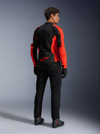Kurtka Alpinestars Viper Air V4, kolor neonowy czerwony i czarny, widok z tyłu na modelu, wyposażona w panele z siatki technicznej i czerwone logo gwiazdy na dole pleców, zestawiona z czarnymi spodniami motocyklowymi i rękawicami, kompletny zestaw szosowy.